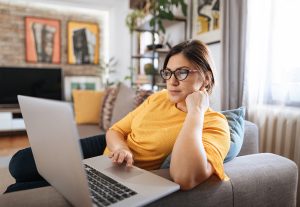 A woman focuses upon her laptop computer at home