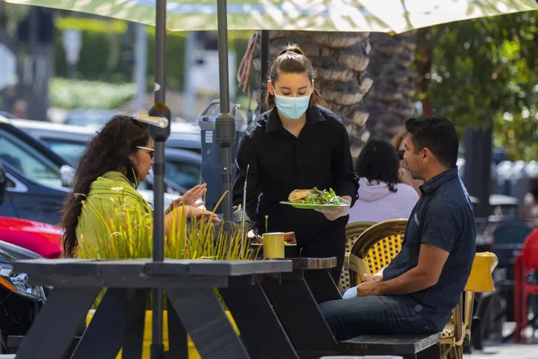 A server brings food to customers at a restaurant in Redondo Beach, Calif. With restaurant employers competing for far fewer applicants, new enticements have become common.