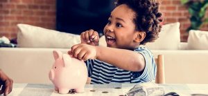 male child putting coins in piggy bank for Quotacy blog 6 Best Things to Buy During Labor Day Sales