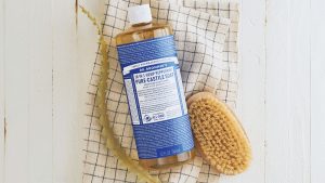 A photo of a bottle of Dr. Bronner’s Pure-Castile Soap next to a bath scrubber.