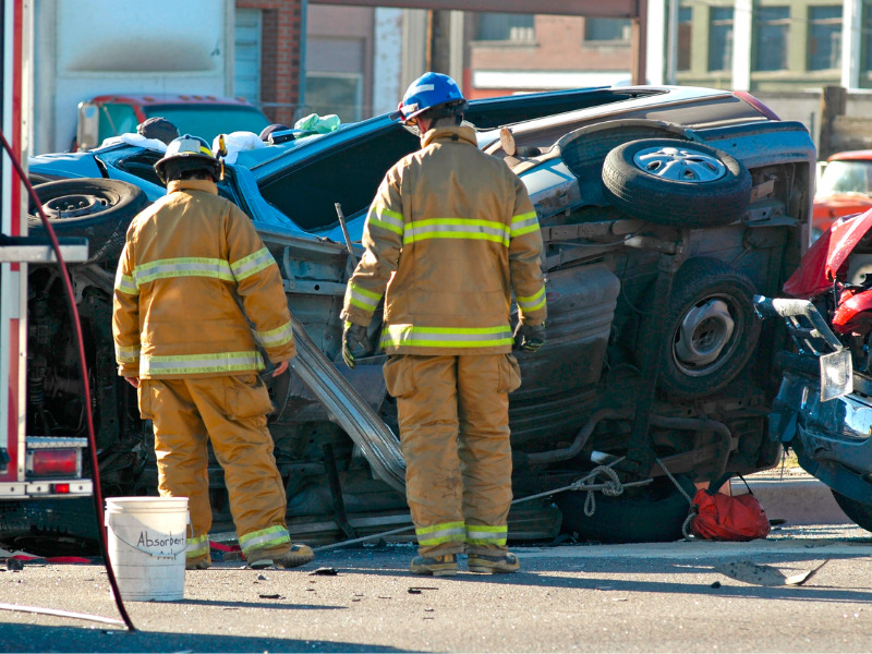 Two emergency service personnel evaluate car accident