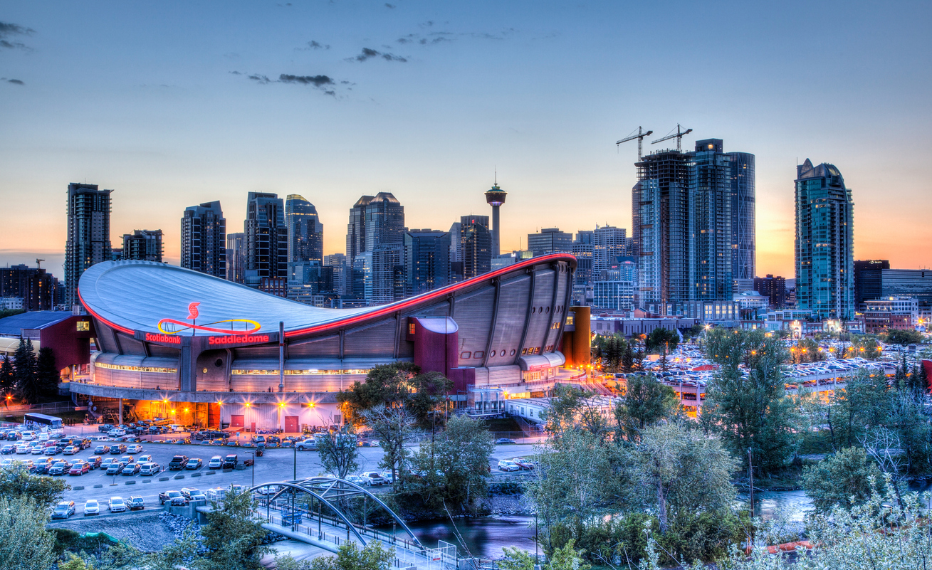 Calgary, Canada - May 23, 2015: Sunset over Calgary's skyline with the Scotiabank Saddledome in the foreground. The dome with its unique saddle shape is home to the Calgary Flames NHL club, and is one of the oldest professional hockey arenas in North America.