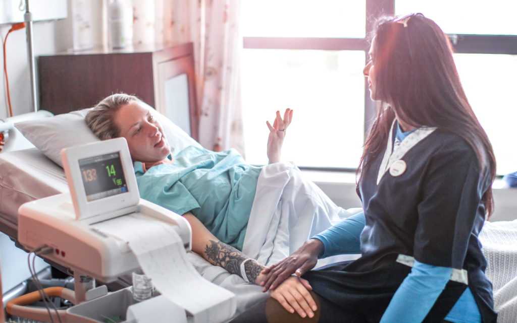 a Young pregnant woman is supported by her Doula before a caesarean section.