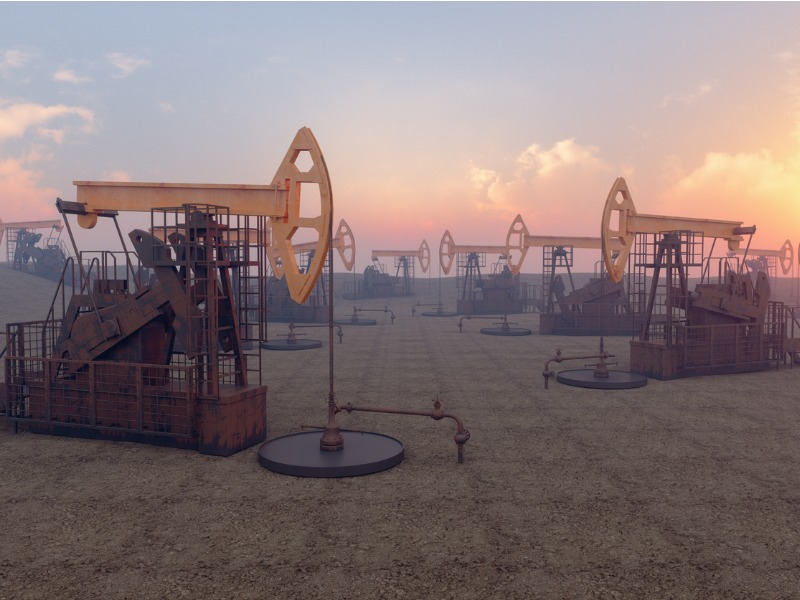 Oil drills in a row on the left and right, in the foreground of a sunset.