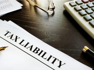 Papers headed with Tax Liability and glasses on a table