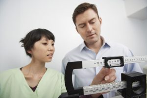 Man standing on weighing scales beside nurse in hospital