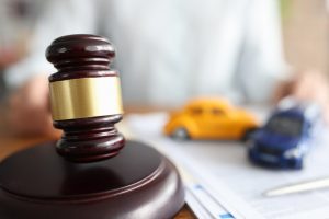 Judge holding hammer near toy cars closeup.