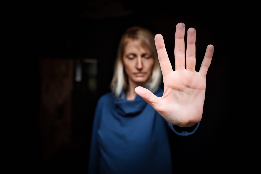 Close-up of a young woman making a stop gesture. Focus on foreground