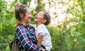 Asian American mom holds young son outdoors