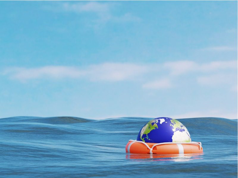 A life preserver floating in the water with a mini earth resting inside of it.