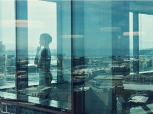 Shot of a businesswoman standing inside a glass building with a reflection of the city in the background