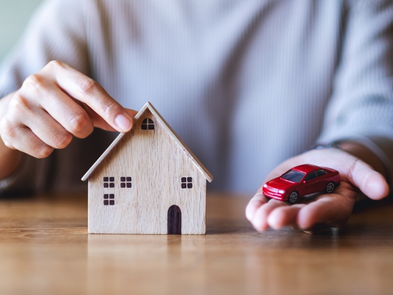 Closeup image of a woman holding and showing wooden house model and car figure model