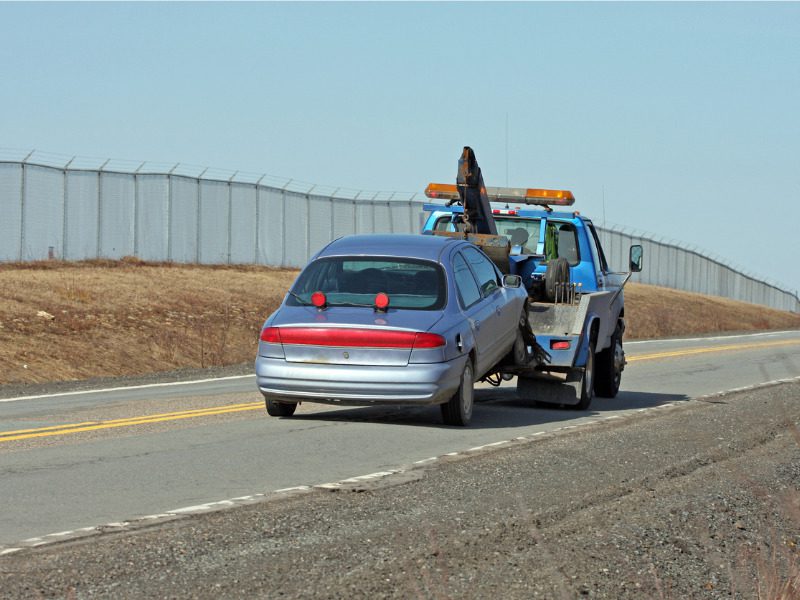 Tow truck towing a vehicle on a two-lane highway