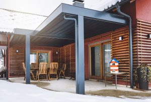 Picturesque family home with red facade combined with wooden details. Hard roof top pergola covering the patio, protecting it from snow. This modern style home gives you a cozy feel, because of wood and warm colors.