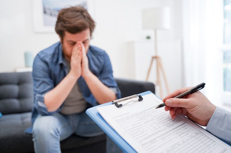 Doctor consulting male patient, working on diagnostic examination of mental illness