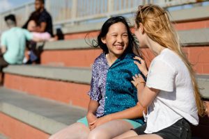 Two friends talking outside the high school on the bleachers