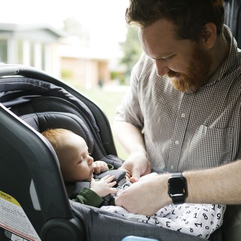 father buckling baby boy 2 3 months in car seat