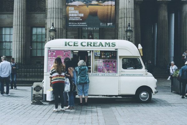 People lined up for ice cream at a van parked outside exhibition building