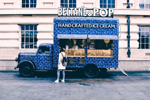 Blue ice cream truck parked with building behind it