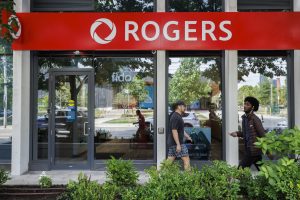 Two individuals walking in front of a Rogers storefront.