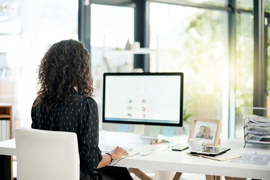 A photo shows a woman working in an office on a computer from behind.