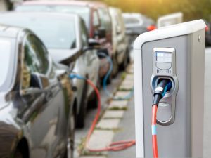 A row of electric vehicles lined up beside a charging station