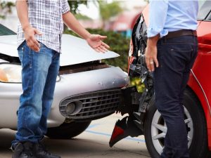 Two drivers argue in front of a silver car which crashed into the back of a red car