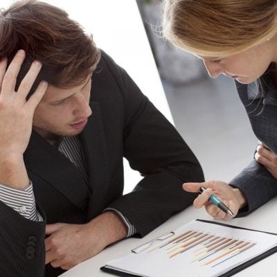 Confused man looking at papers while woman explains