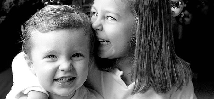 Image of big sister with arm around shoulder of her little brother for Quotacy blog What Is a Life Insurance Child Rider?