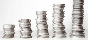 Image of coins stacked up in five piles for Quotacy blog Little Money Saving Changes You Can Make Every Month.