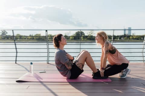 Young man with tattoos doing core workout on the dock