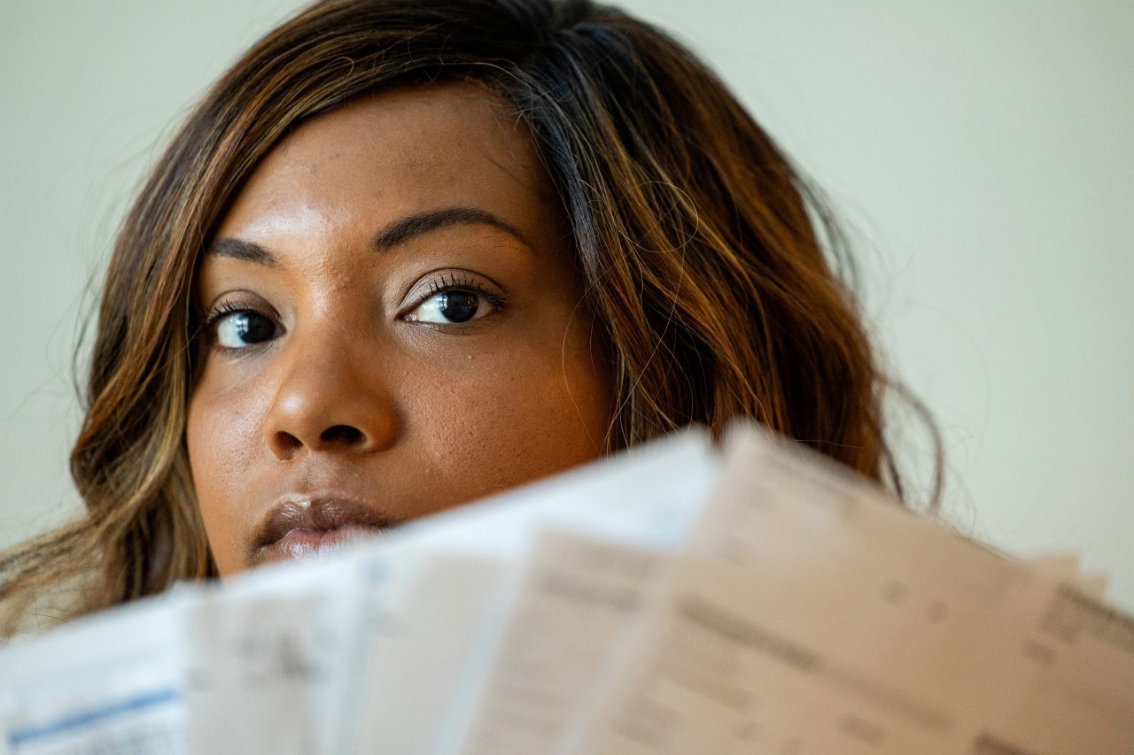 A photo shows Dani Yuengling holding up medical bills in front of her face.