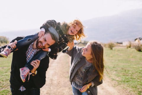 Family walking together while dad holds toddler on his shoulders