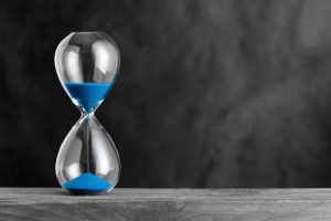 Hourglass with blue sand on the wood