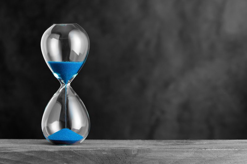 Hourglass with blue sand on the wood