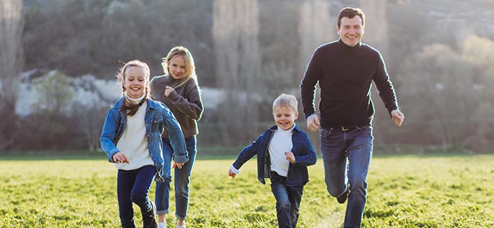 mom dad and children running for Quotacy blog cost of $100,000 life insurance policy