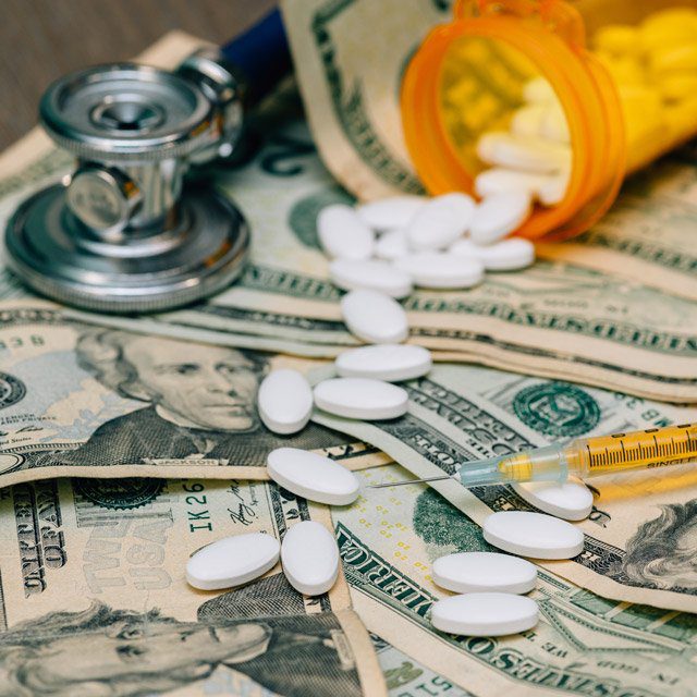 Pills, bottle and stethoscope on pile of money