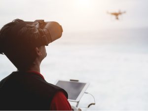 A person wearing goggles and controlling a drone in the sky