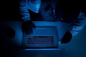 Hacker thief with laptop in darkness