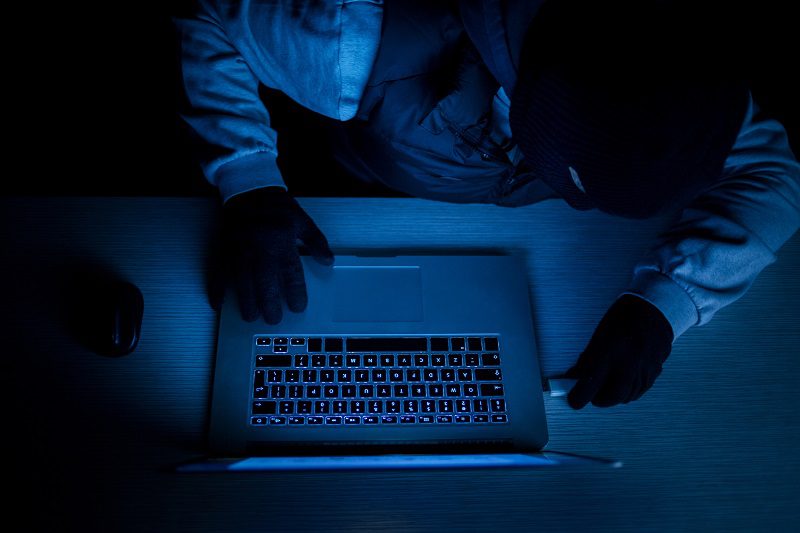 Hacker thief with laptop in darkness