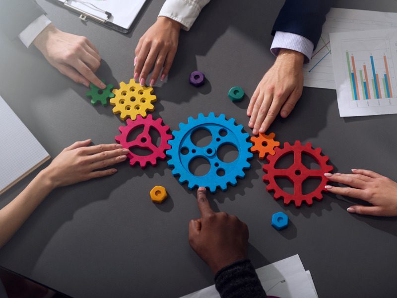 Business team connecting pieces of a gear, symbolizing partnership