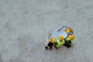 Top View of Architects and Engineer Workers With Blueprints discussing at a construction site