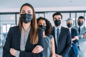 Group portrait of multiracial business persons with protective face masks standing together in the office.