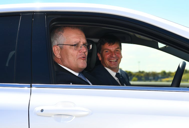 two smiling men sit in car