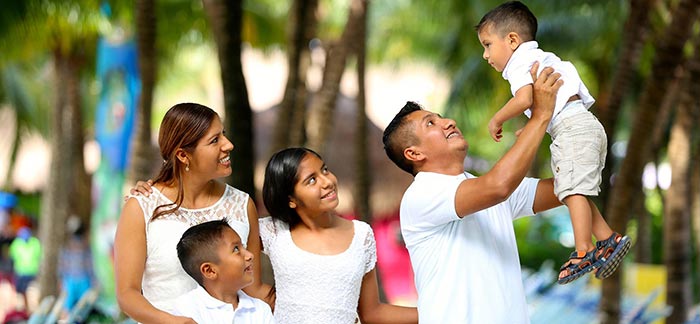 Image of father holding son up in air with family looking on for Quotacy blog When Should Someone Else Own My Life Insurance?