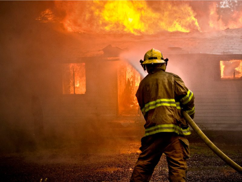 Firefighter spraying water at a house fire