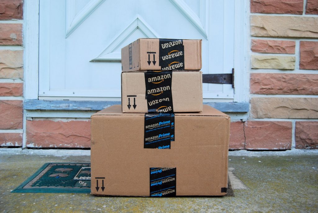 Three Amazon boxes stacked in front of a residential door.