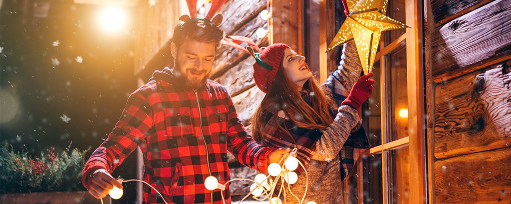 happy couple placing Christmas decorations outside their home