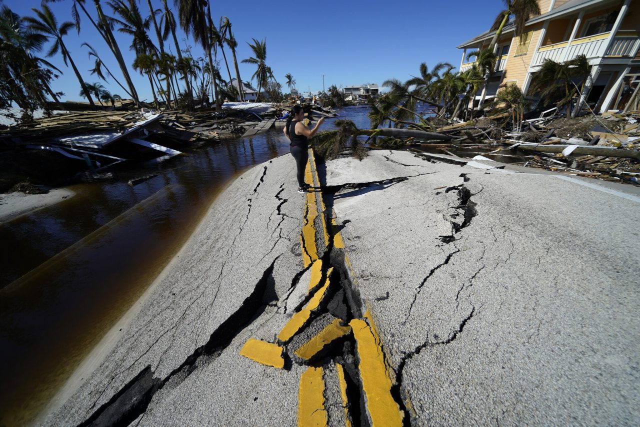 Mara Elieser, whose husband kept a boat docked nearby, takes photos at the destroyed bridge leading to Pine Island, in the aftermath of Hurricane Ian in Spring Hill, Fla., Sunday, Oct. 2, 2022. The only bridge to the island is heavily damaged so it can only be reached by boat or air. (AP Photo/Gerald Herbert)