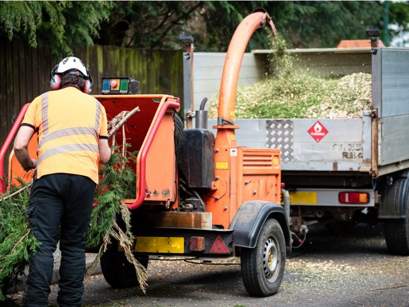 Tree shredder and specialized dumper truck on a city street